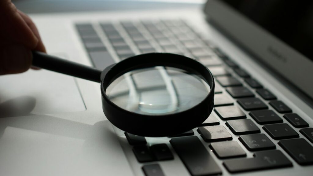 Magnifying glass next to a laptop, showing how to read reviews carefully