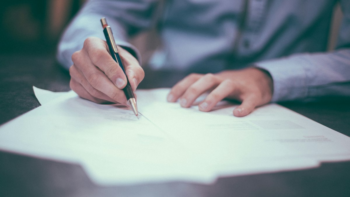 Man signing a migration services agreement on paper